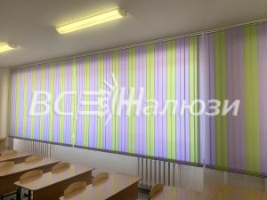 Разноцветные полосатые вертикальные жалюзи вдоль окон учебного класса