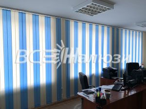 Сине-белые полосатые вертикальные жалюзи над рабочим местом
