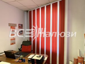 Красно-белые вертикальные жалюзи в углу небольшого кабинета