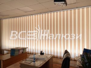 Персиковые вертикальные жалюзи вдоль длинного окна над столами