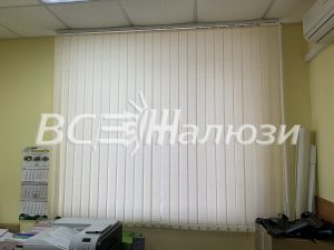 Кремовые вертикальные жалюзи во всю ширину окна кабинета
