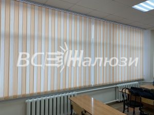 Бежево-белые полосатые вертикальные жалюзи вдоль окна учебного кабинета