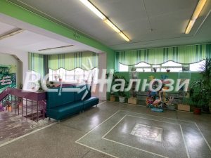 Зелёные вертикальные жалюзи вдоль окон холла с цветами