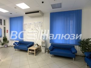 Синие вертикальные жалюзи в зале ожидания с синими диванами