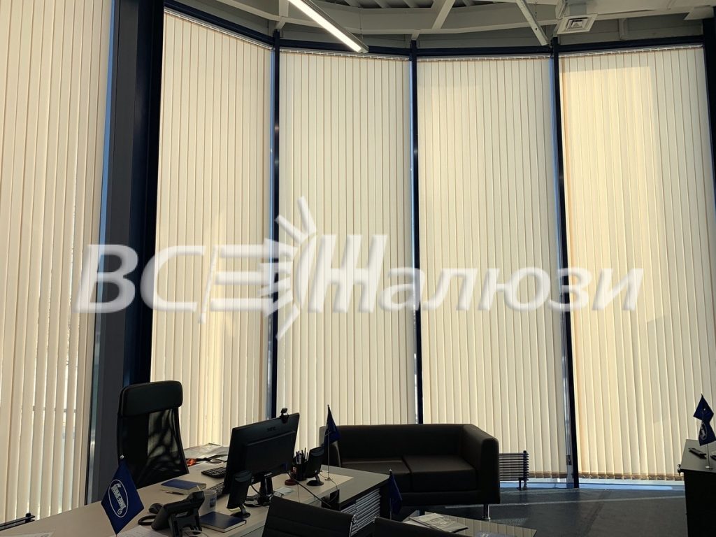 Кремовые вертикальные жалюзи на изогнутом панорамном остеклении офиса