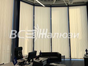 Кремовые вертикальные жалюзи на изогнутом панорамном остеклении офиса