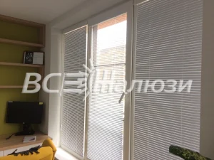 Белые жалюзи на балконной двери и окне комнаты