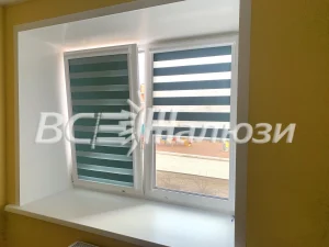 Бирюзовые шторы зебра на окне в белом проёме