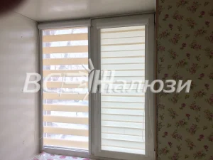 Светло-бежевые шторы зебра на балконном блоке, обои в цветочек