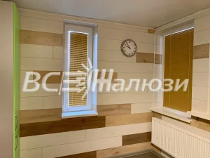 Золотистые жалюзи на узком и широком окнах, стены под дерево