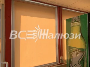 Оранжевая рулонная штора на витрине магазина, вид с улицы
