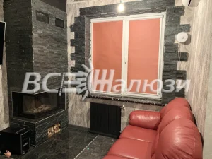 Терракотовые рулонные шторы в гостиной с камином и кожаным диваном