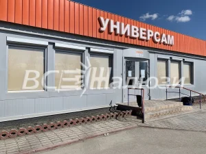 Бежевые рулонные шторы в окнах универсама, съёмка снаружи