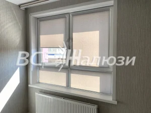 Серо-бежевые рулонные шторы на окне над радиатором