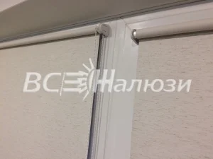 Вал и светлое полотно рулонной шторы крупным планом