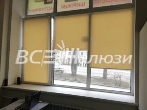 Жёлтые рулонные шторы на трёхстворчатом окне, за стеклом улица