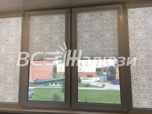 Бежевые рулонные шторы с ажурным узором подняты до середины