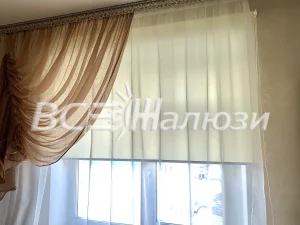Кремовая полупрозрачная рулонная штора и золотистая портьера на окне