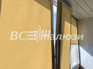 Песочные рулонные шторы закрывают остекление балкона, вид под углом