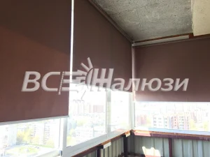 Коричневые рулонные шторы на остеклении балкона с видом на город