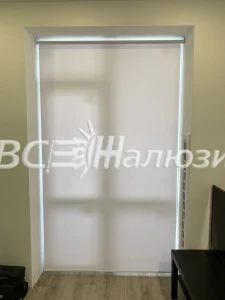Белая рулонная штора закрывает высокий узкий проём