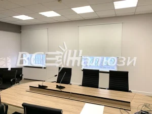 Светлые рулонные шторы на окнах переговорной с длинным столом