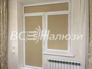 Бежевые рулонные шторы на окне и балконной двери, рядом радиатор
