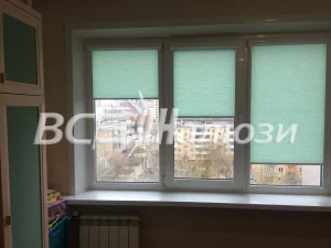 Мятные рулонные шторы на трёх створках окна светлой комнаты