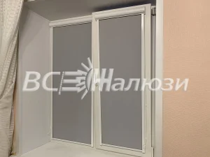 Серые рулонные шторы полностью опущены на двух створках окна