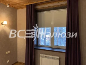 Светло-серые рулонные шторы между сливовыми портьерами у окна