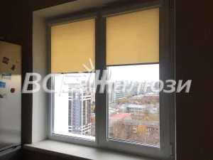 Жёлтые рулонные шторы на окне с видом на город сверху