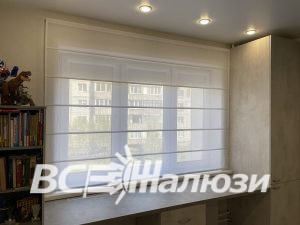 Белая римская штора закрывает верхнюю половину широкого окна