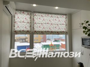 Цветочная римская штора собрана складками, за окном зимний двор
