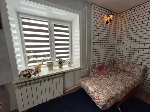 Серо-белая «Зебра» в комнате с кирпичной стеной и диваном