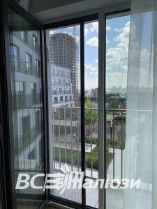 Москитная сетка плиссе на балконной двери с видом на город