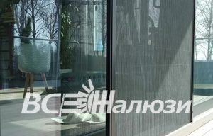 Москитная сетка плиссе задвинута наполовину на раздвижном остеклении