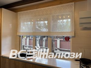 Полупрозрачная штора с узором над кухонным окном у мойки