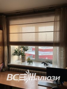 Бежевая штора закрывает верх окна над рабочим столом