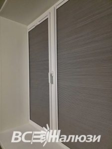 Серая штора гофре в раме на балконной двери