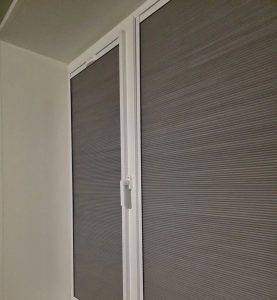 Серая штора гофре в раме на балконной двери