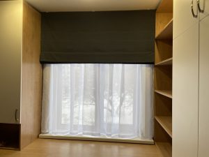 Тёмная штора и тюль на окне в нише со стеллажом